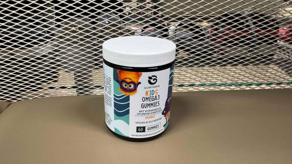Vor einem Gitter steht die Packung des getesteten Omega-3 für Kinder.