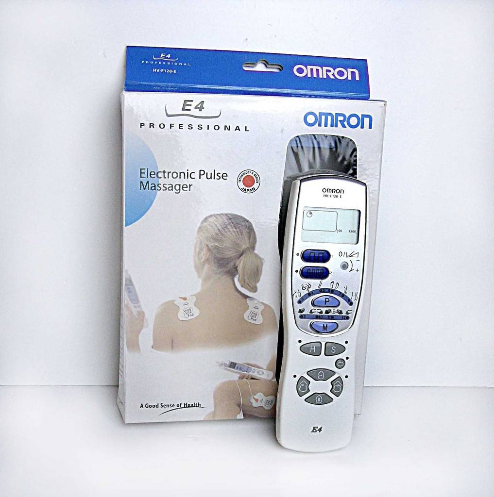 Das Reizstromgerät im Test steht vor seiner Verpackung von OMROM.