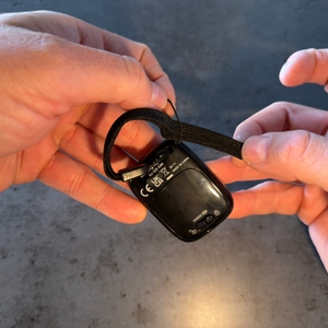 Eine Hand befestigt die Handschlaufe vom Omron-Schrittzähler