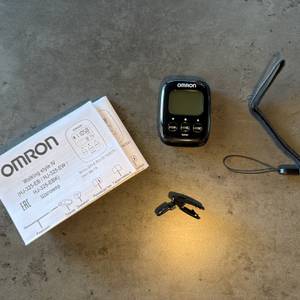 Der Lieferumfang vom Omron-Schrittzähler liegt auf einem Tisch