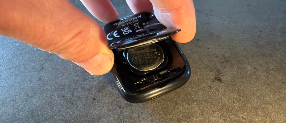 Eine Hand öffnet das Batteriefach vom Omron-Schrittzähler