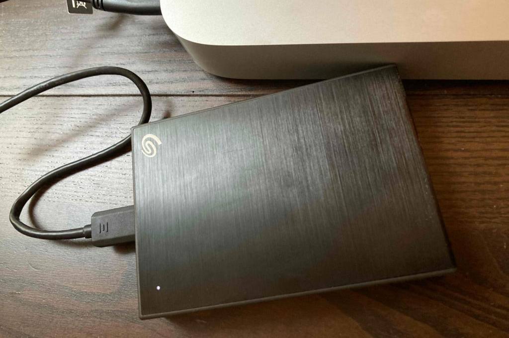 Im Test: eine externe Festplatte mit 5 TB Speicherplatz liegt an einer Computereinheit angeschlossen auf einem Holzuntergrund.
