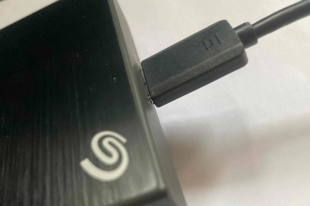 Ein USB-Kabel steckt in einer getesteten externen Festplatte mit 5 TB Speicherplatz.