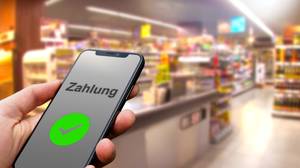 Online-Banking-Software-Test: Eine Person steht in einem Supermarkt und hält ein Smartphone in der Hand, mit dem sie gerade eine Zahlung tätigt.