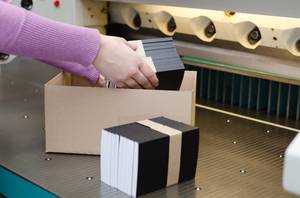 Online-Druckereien getestet: Ein Frau verpackt mehrere Druckprodukte in einem Karton.