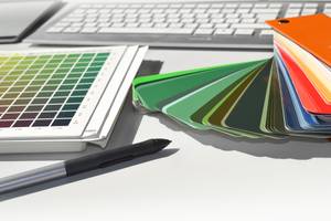 Online-Druckerei-Test: Mehrere Produkt- und Farbmuster liegen auf einem Tisch neben einer Tastatur.