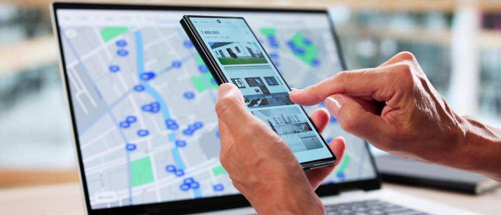 Eine Person prüft ein Immobilienportal auf dem Smartphone.
