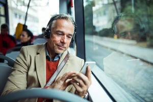 Onlinekurse im Test: Ein Mann lernt mit seinem Smartphone im Bus bei einem Onlinekurs.