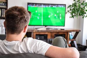 Online-TV-Test: Ein Mann sitzt auf der Couch und schaut über seinen Fernseher eine Fußball-Übertragung an.