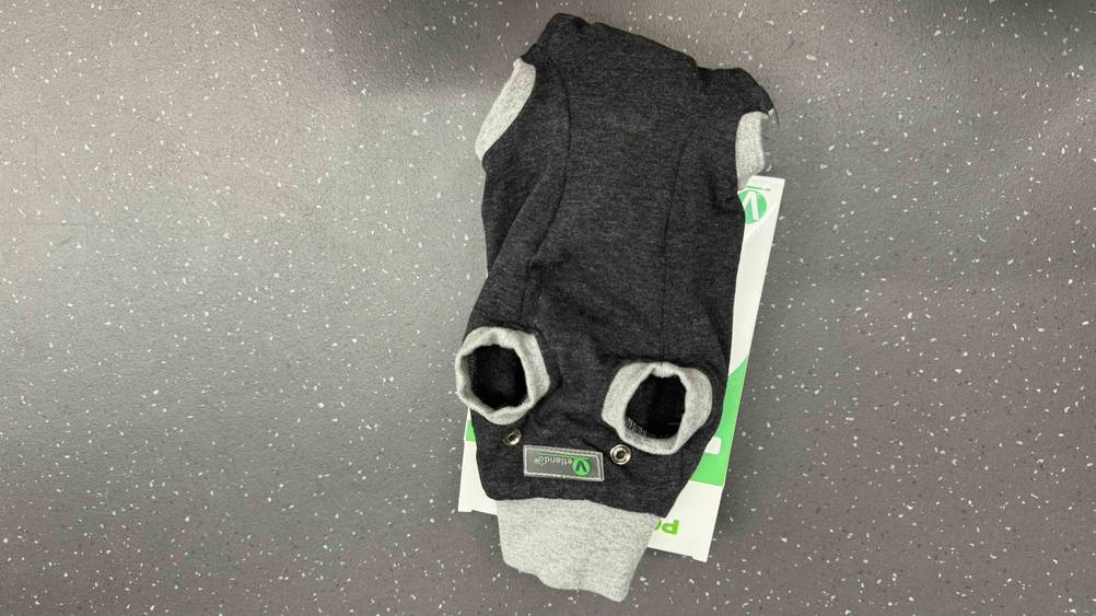 Getestet: Ein OP-Body Hund von unten mit Logo auf einer grauen Fläche.