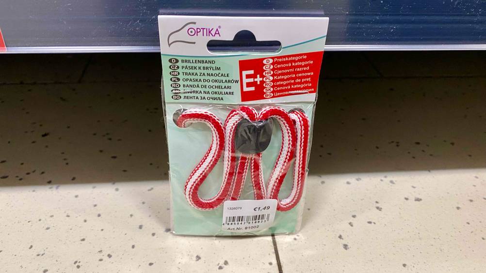 Brillenband getestet: Ein verpacktes Band lehnt an einem Regalbrett.