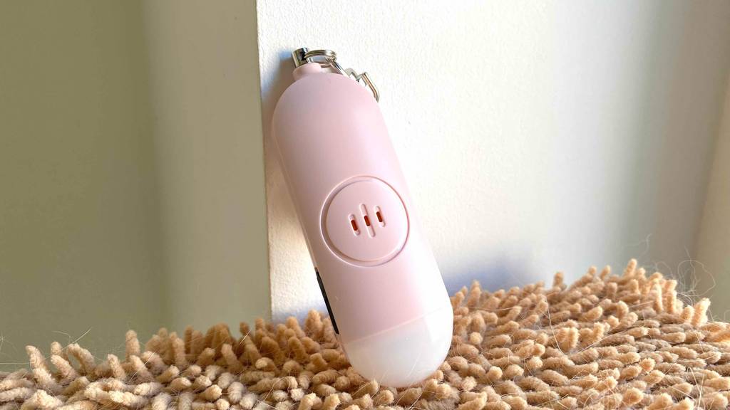 Detailansicht eines getesteten Taschenalarms, der an eine weiße Wand lehnt.