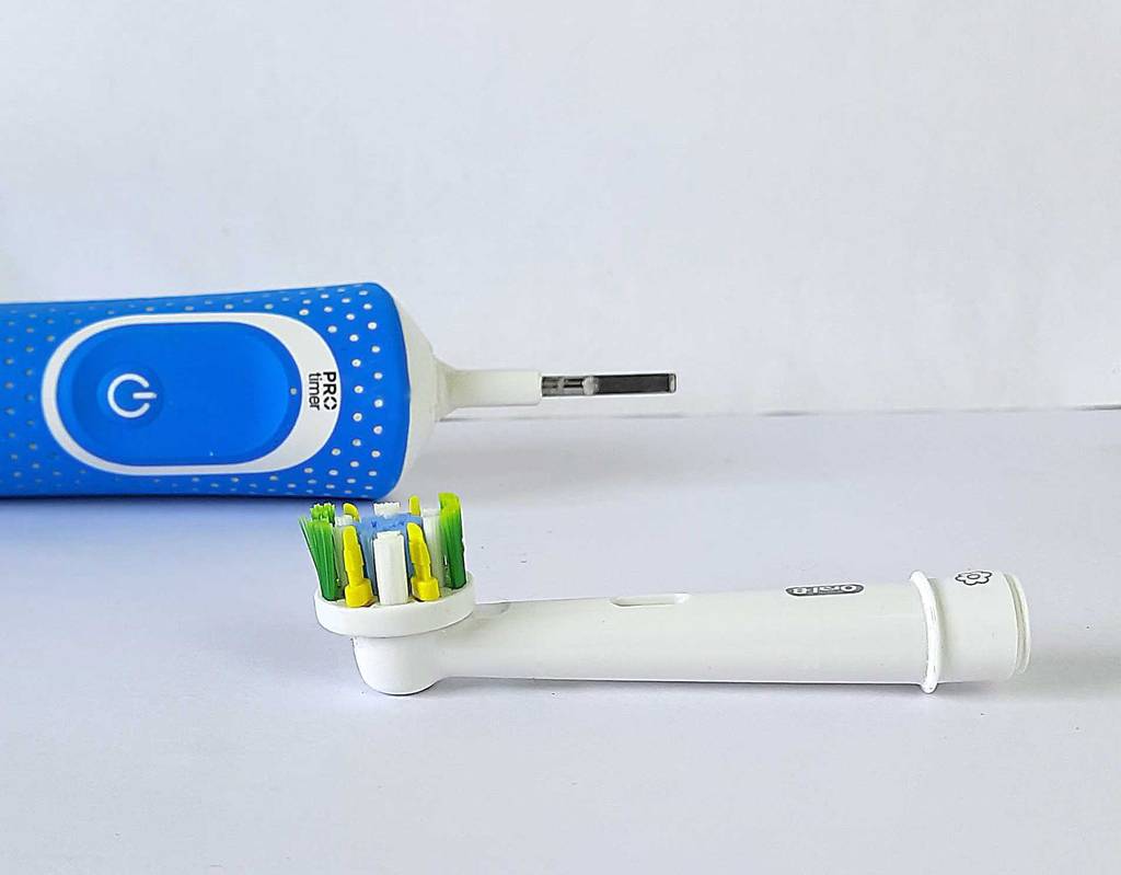 Ein Bürstenkopf liegt vor der getesteten rotierenden Zahnbürste.