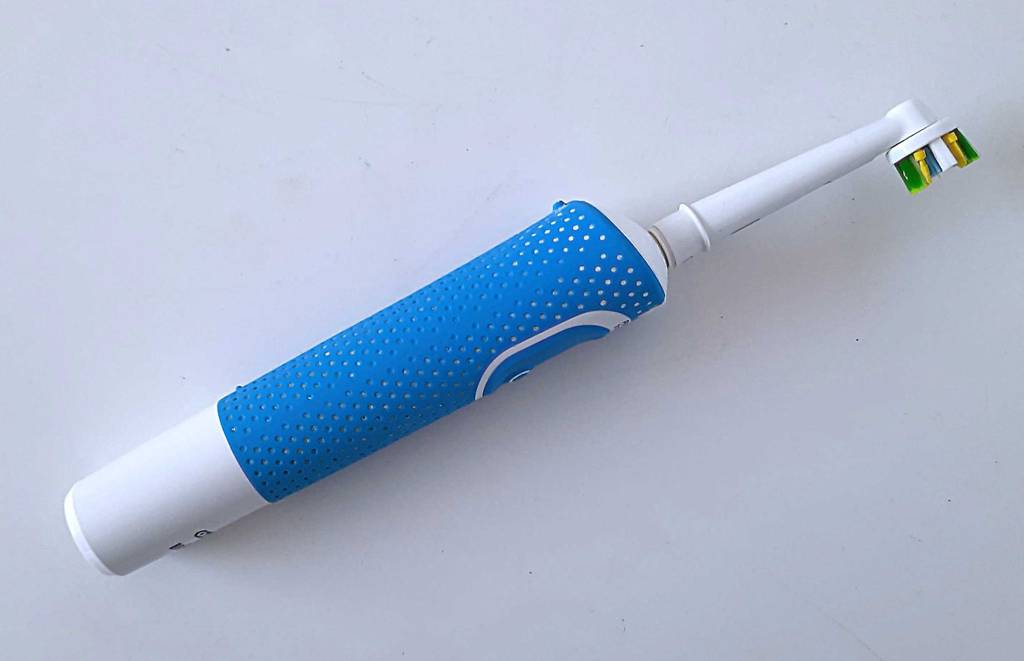 Seitenansicht von oben auf eine rotierende Zahnbürste, die getestet auf einer weißen Fläche liegt.