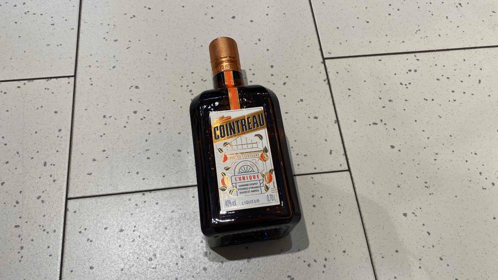 Ein getesteter Orangenlikör aus Frankreich befindet sich in einer Glasflasche auf dem Boden.