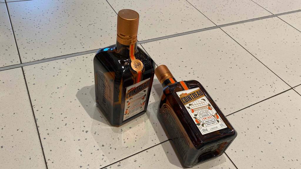 Zwei Flaschen getestetes Orangenlikör befinden sich auf dem Boden. 