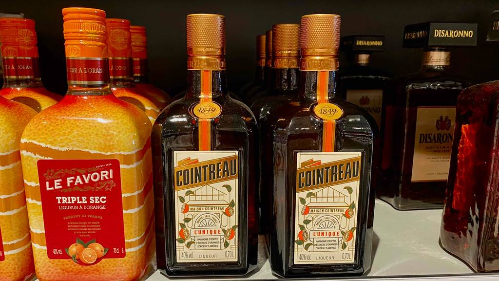 Mehrere Flaschen getestetes Orangenlikör befinden sich im Supermarktregal. 