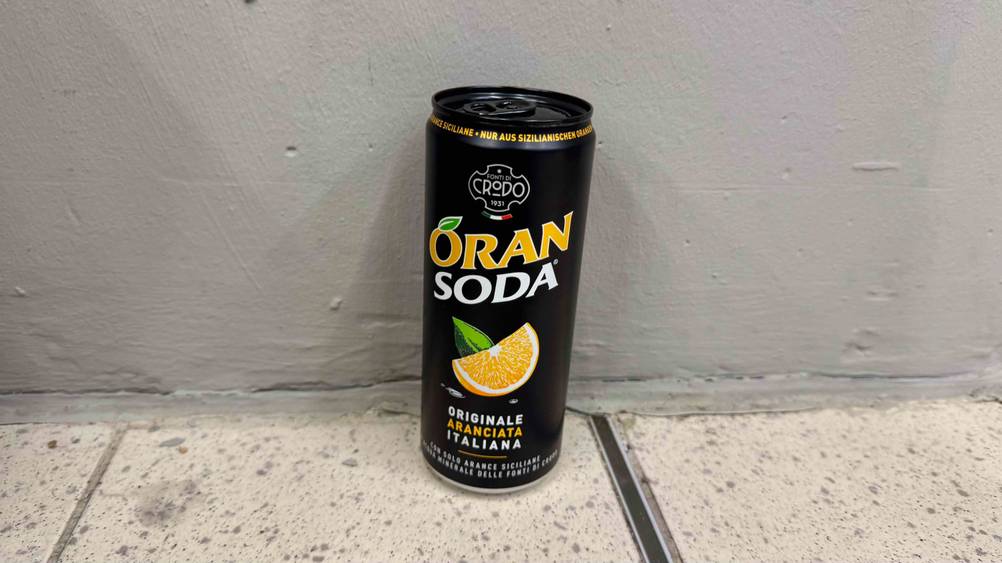 Orangenlimonade getestet: Eine Dose von schräg oben vor einer grauen Wand.