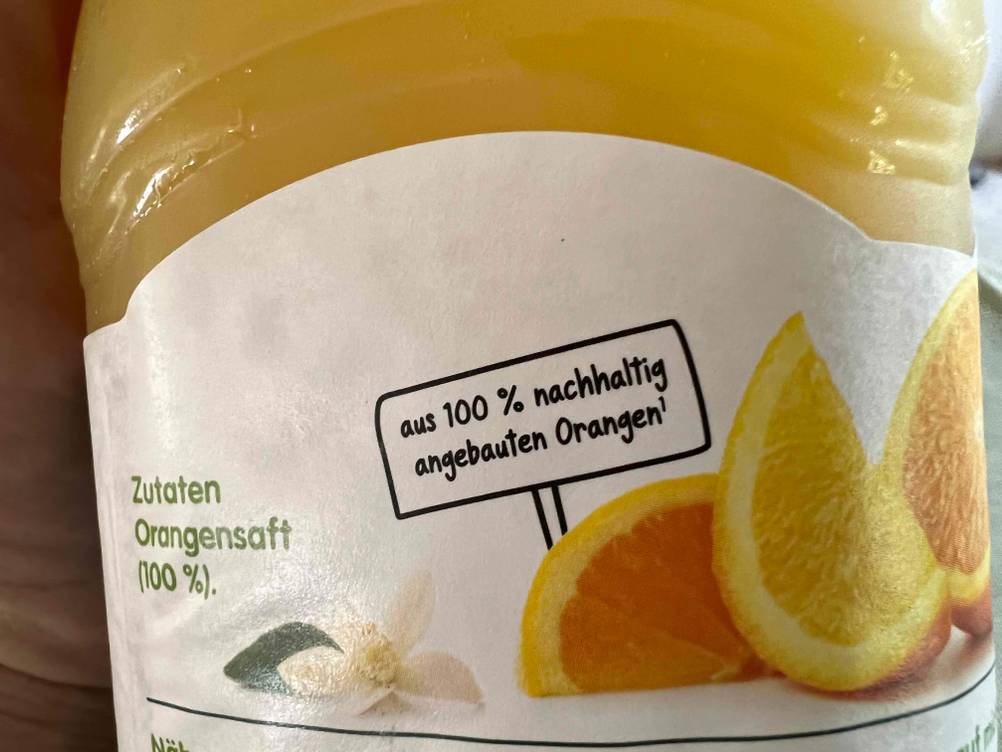 Im Test: Nahaufnahme der Information auf einer Flasche Orangensaft zur Nachhaltigkeit.