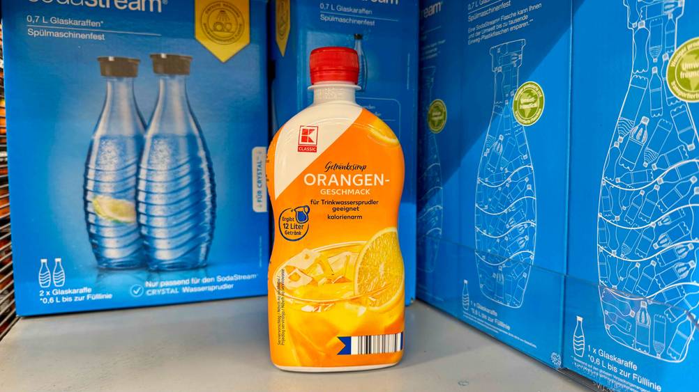 Orangensirup im Test: Eine Flasche von vorne vor mehreren blauen Kartons.