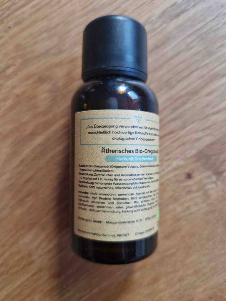 Oregano-Öl im Test: Rückseite einer Glasflasche liegt auf dem Holztisch. 