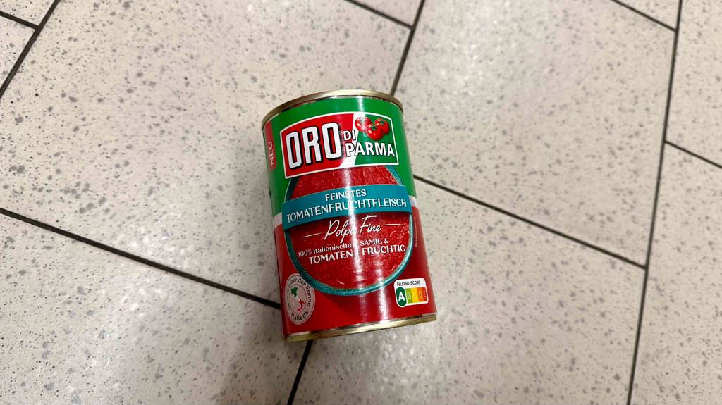 Eine Dose getestete Tomatensauce liegt auf einem Fliesenboden.