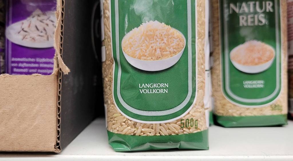 Getesteter Vollkornreis in der 500-g-Packung steht auf einem Verkaufsregal zwischen weiteren Reissorten in der Kunststoffverpackung.