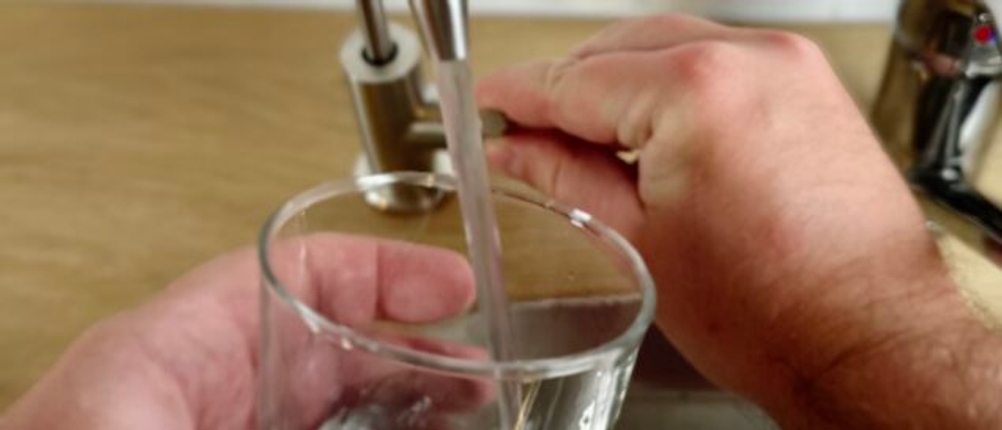 Ein Glas wird mit gefiltertem Trinkwasser aus einem an einer Osmoseanlage angeschlossenen Wasserhahn befüllt.