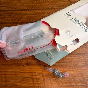 Eine Hand zieht die Osprey Hydraulics LT aus der Verpackung