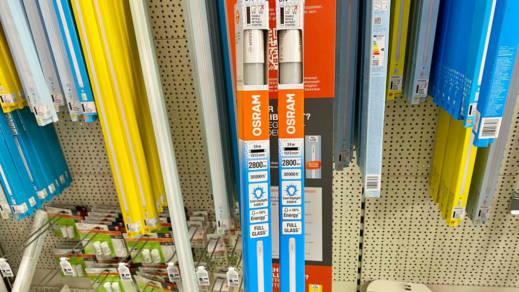 LED-Röhre 150cm im Test: Mehrere verpackte Röhren hängen und stehen nebeneinander in einem Lochregal.