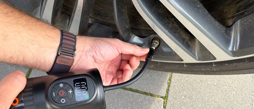 Eine Hand steckt den Anschluss vom Osram TyreInflate 2000 in einen Autoreifen