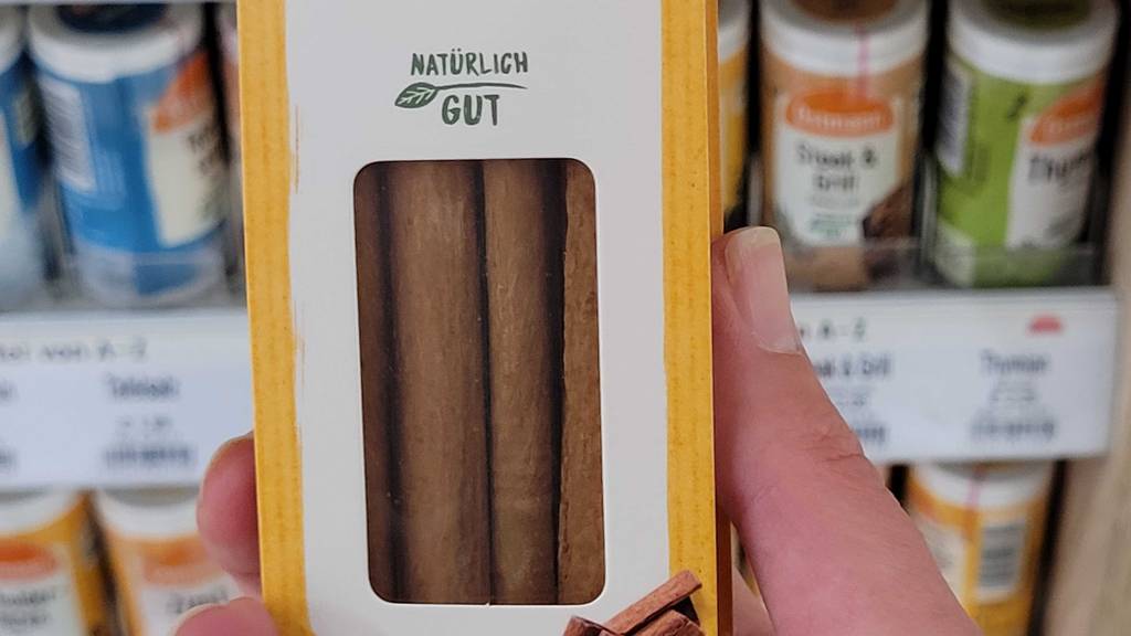 Zimtstangen im Test: Nahaufnahme der Packung in einer Hand vor einem Gewürzregal.
