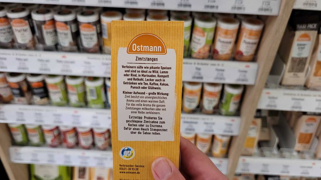 Zimtstangen-Test: Nahaufnahme der Packung von Ostmann in einer Hand vor dem Gewürzregal eines Supermarktes.