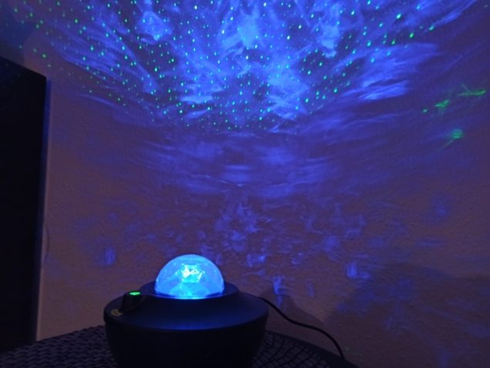 Blaue Farbe und Sterne werden in einem dunklen Raum mit einem Sternenhimmel-Projektor erzeugt.
