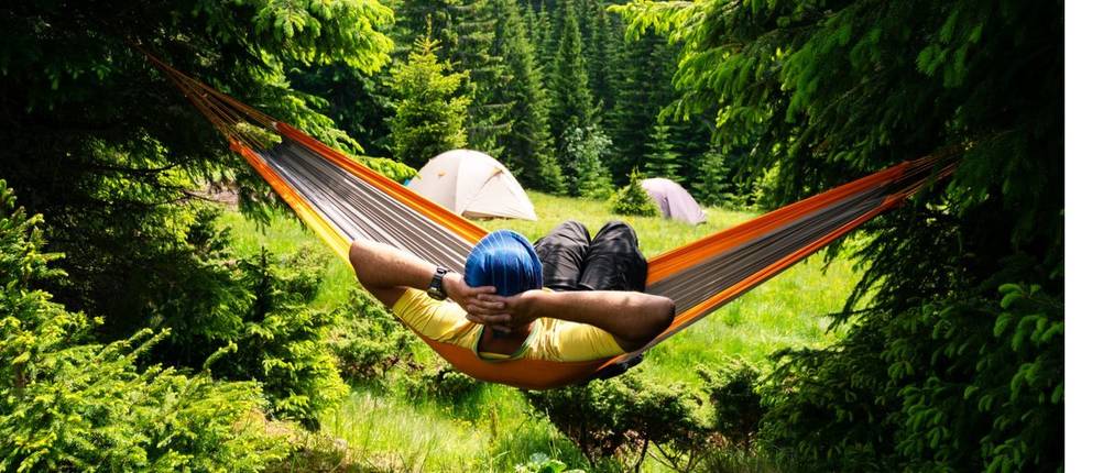 ein Mensch in einer Hängematte entspannt in der Natur