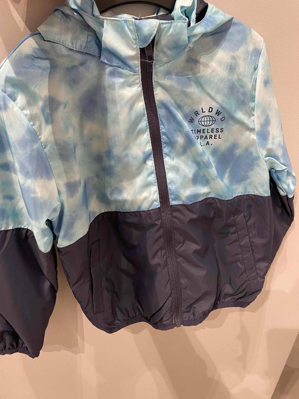 Kinder-Outdoor-Jacke getestet: Eine Jacke hängt vor einer hellen Wand auf einem Bügel.