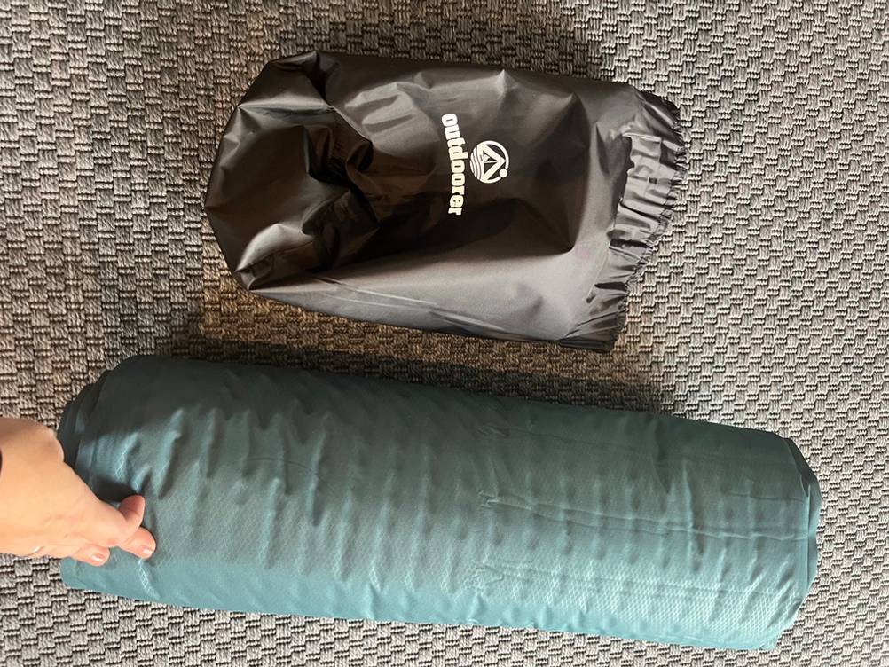 Die Outdoorer Trek Bed 2 liegt zusammengerollt neben ihrer Schutzhülle