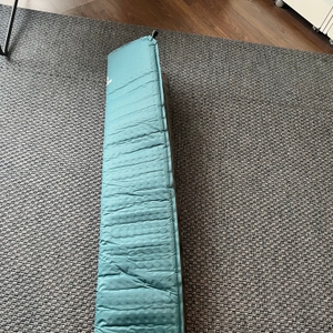 Die abgerollte Outdoorer Trek Bed 2 liegt auf einem Teppich