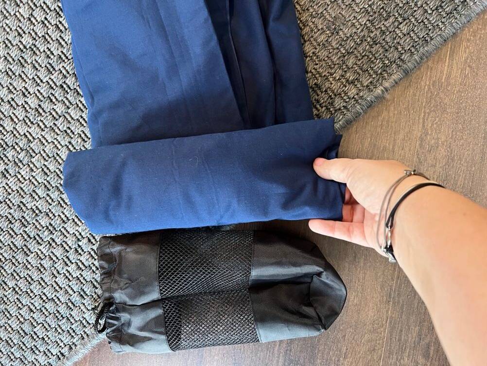 Hüttenschlafsack Outdoro-HS-11BL wird neben einer Transporttasche eingerollt