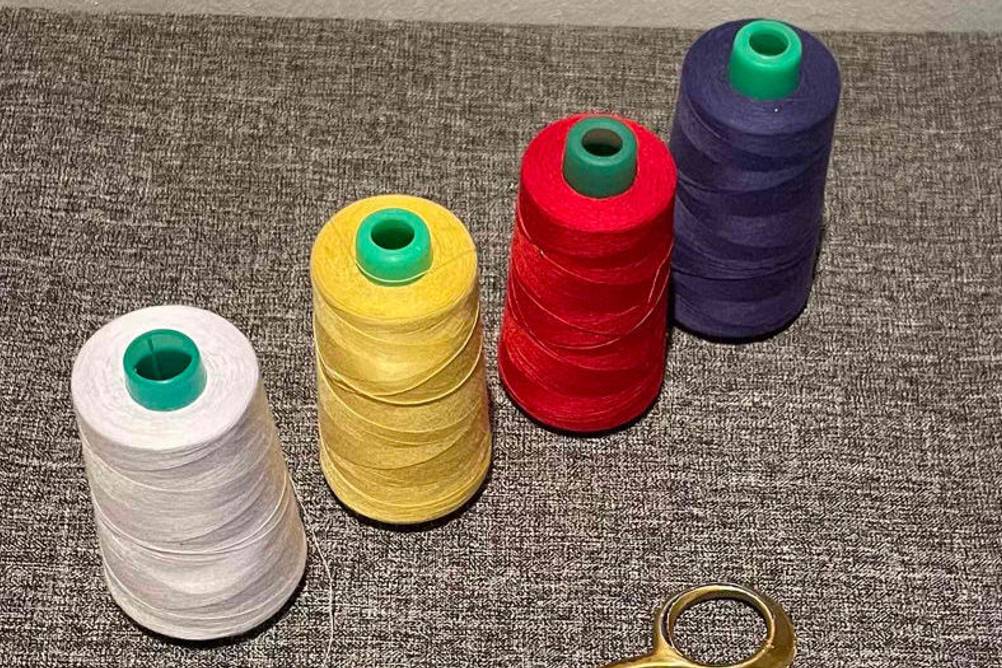 Der Overlockgarn im Test ist in vier Farben neben einer Schere zu sehen.