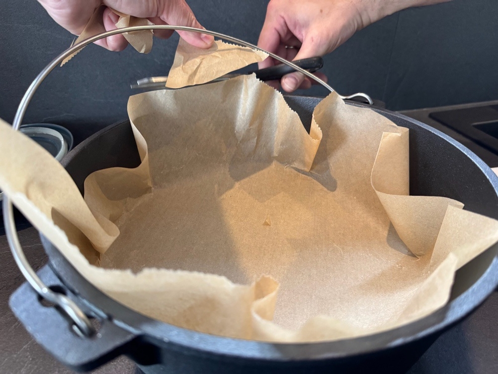 Mit einer Schere wird ein Stück Backpapier an die Form des Overmont-Feuertopf angepasst