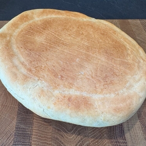 Weißbrot aus dem Overmont-Feuertopf liegt falschherum auf einem Holzbrett