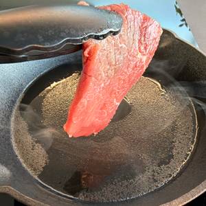 Ein rohes Steak wird in die Overmont-Gusseisenpfanne gelegt