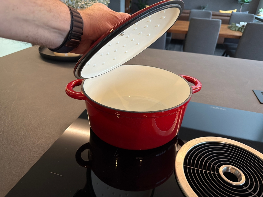 Eine Hand hebt den Deckel vom Overmont-Schmortopf hoch