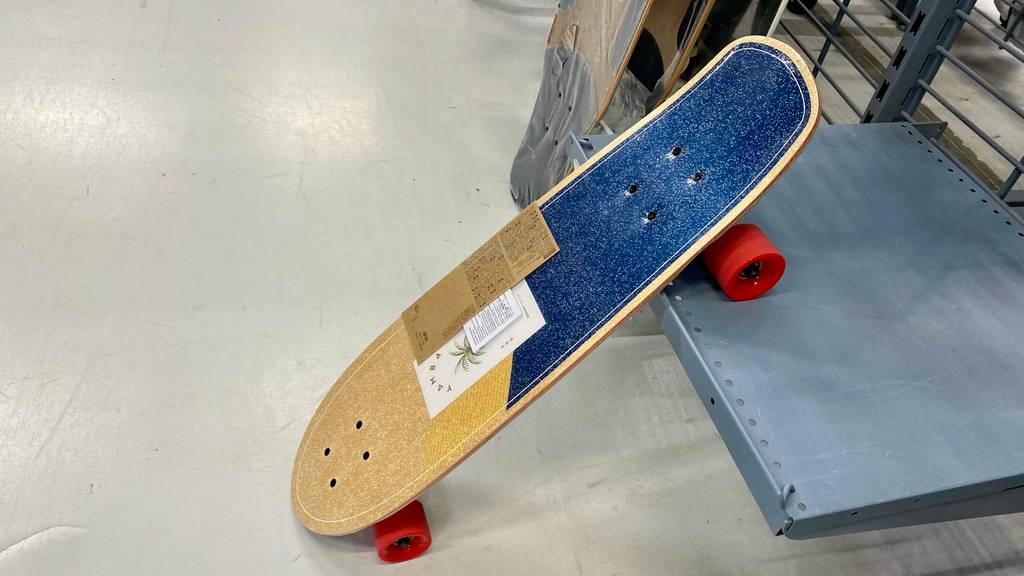 Longboard-Test: Ein Longboard von der Seite betrachtet lehnt halb an ein Regal.