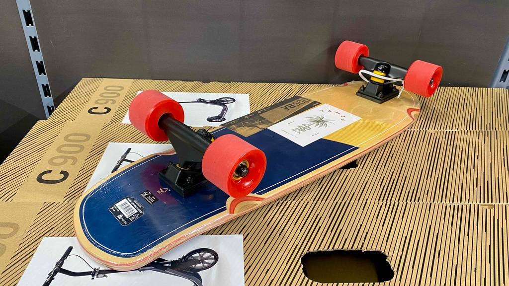 Ein getestetes Longboard liegt umgedreht mit Aufklebern bestückt.