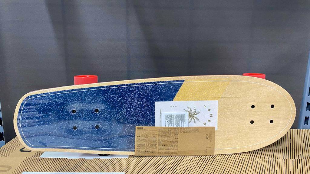 Ein Longboard im Test steht mit der Standfläche nach vorn auf einer Holzfläche.