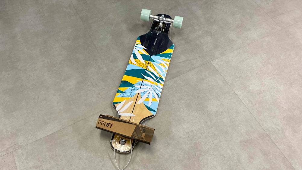 Getestetes Mini-Longboard liegt auf einem grauen Untergrund.