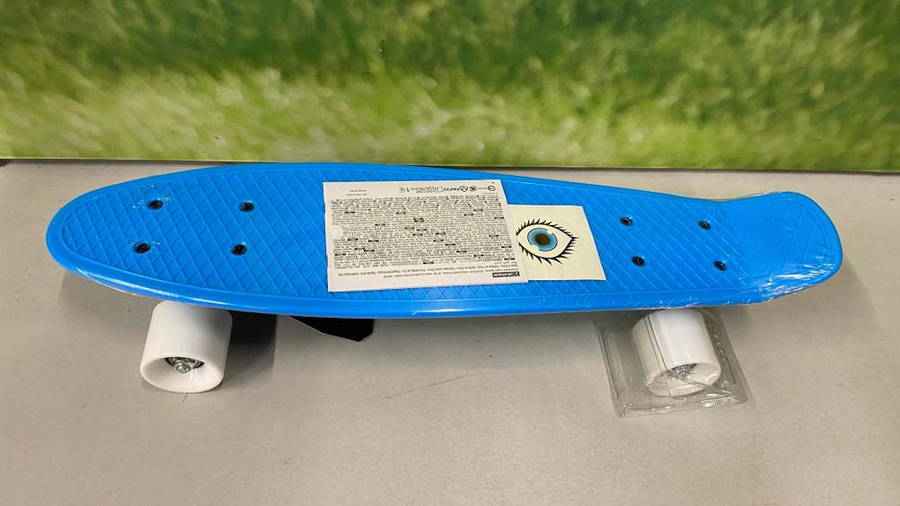 Im Test: ein Skateboard für Kinder in blauem Design steht auf seinen weißen Rädern in einem Ausstellungsbereich.