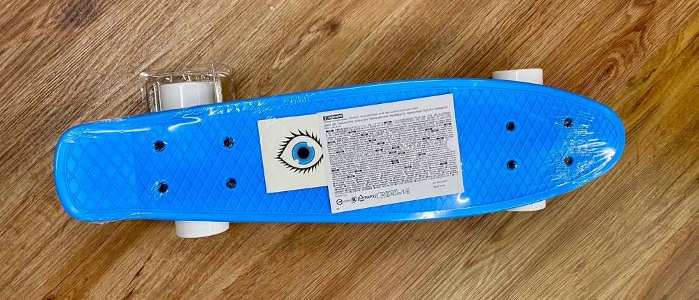 Im Test: Ein eingeschweißtes Skateboard für Kinder in blau von oben auf einem Holzboden.
